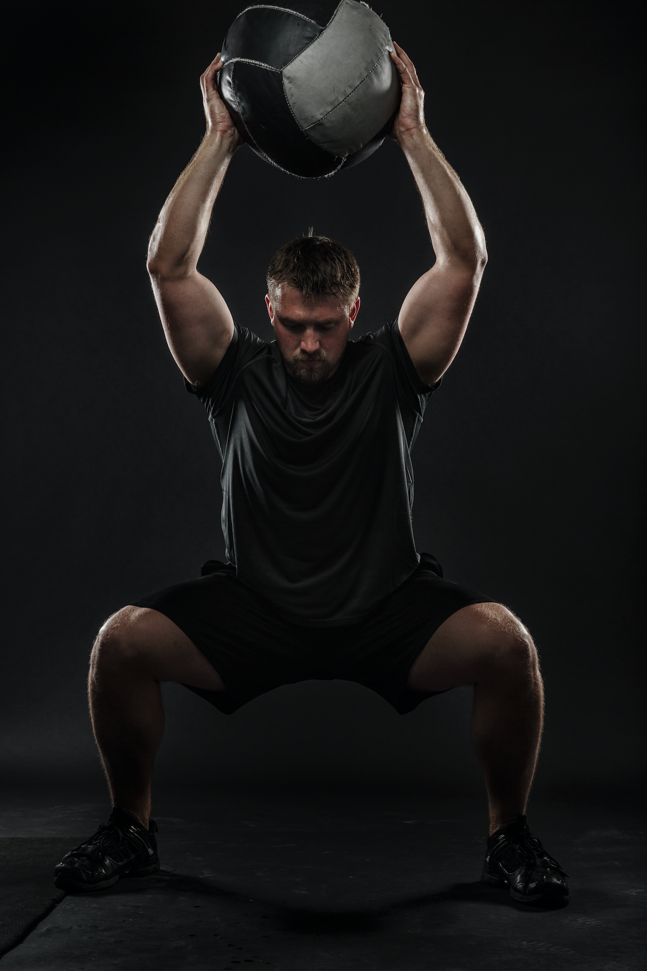 man performing a medicine ball squat