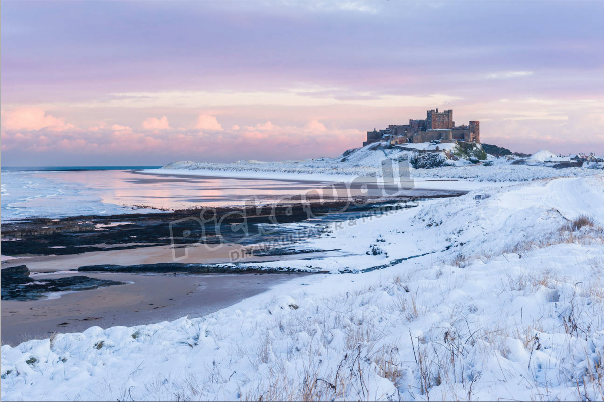 Snow covered winter scene at sunset, Bamburgh castle, YK