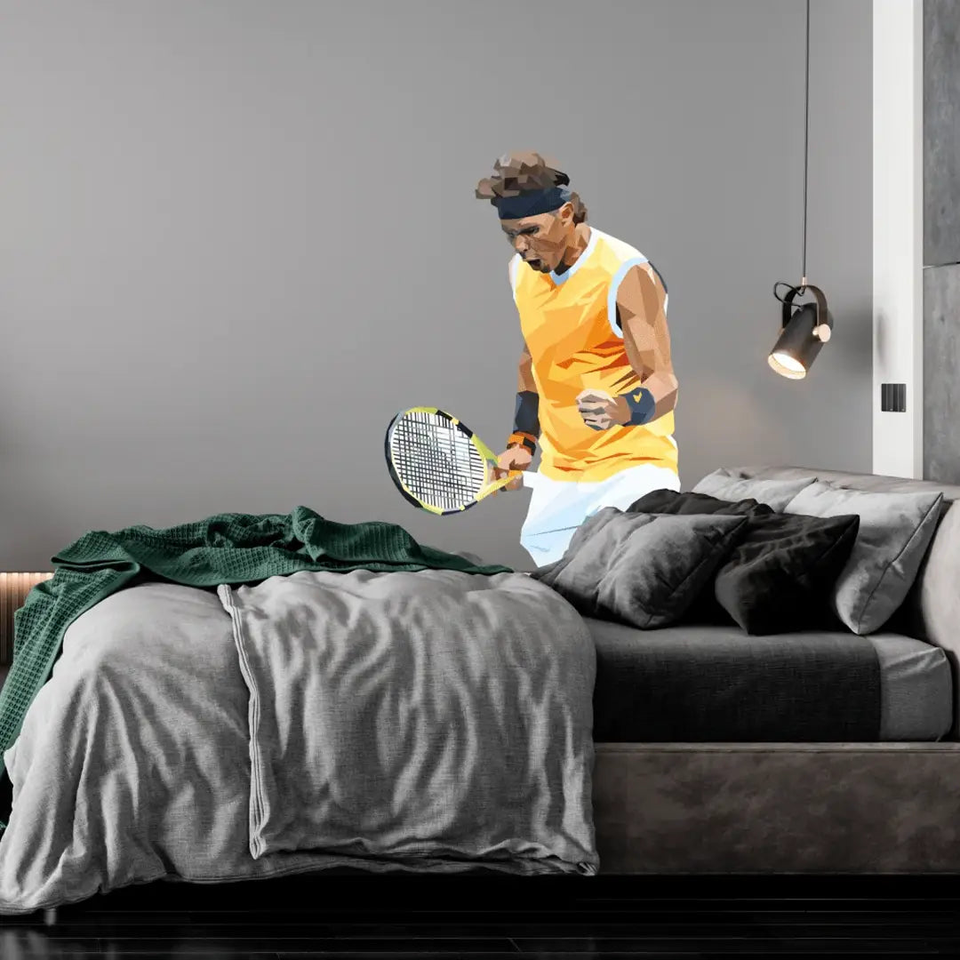 A large wall decal of tennis player Rafael Nadal is displayed on a grey bedroom wall above a bed with grey bedding and dark pillows. The decal depicts Nadal in a yellow and white sleeveless shirt, white shorts, and a black headband, holding a tennis racket.