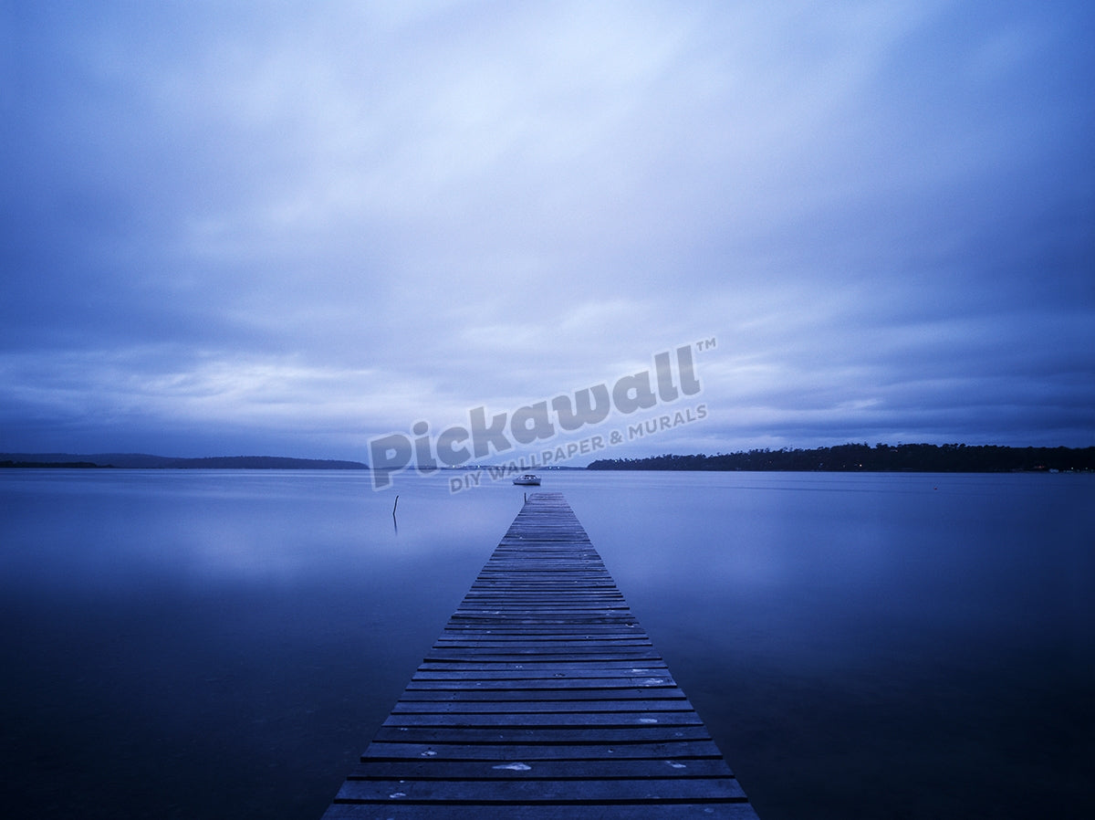 Jetty with still water and clouds.