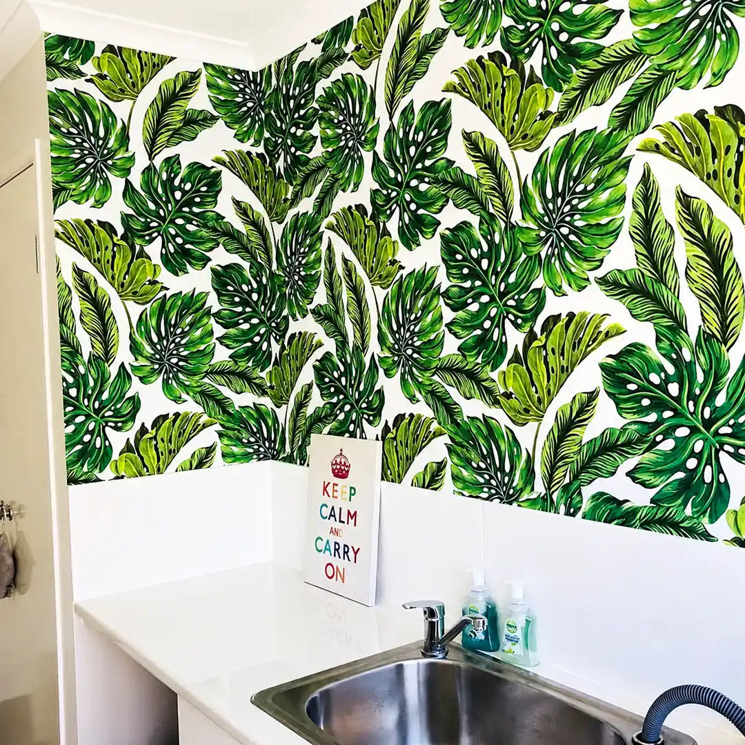 Bright laundry room featuring bold tropical leaf wallpaper, a white benchtop and stainless-steel sink