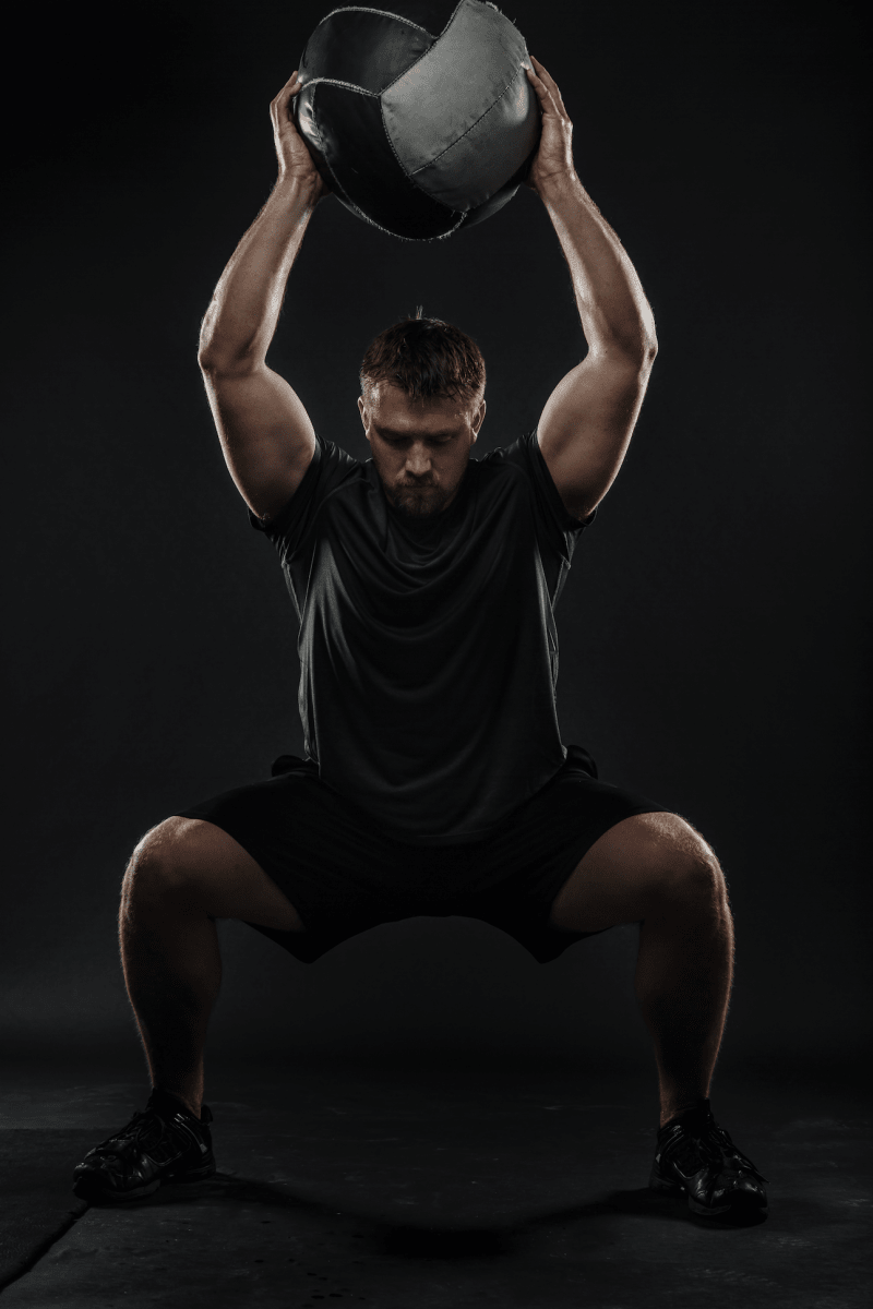 man performing a medicine ball squat - Pickawall